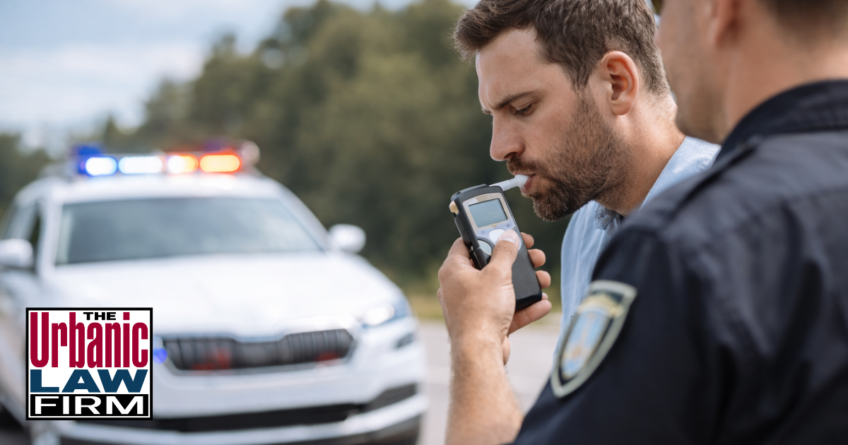 Daytime Oklahoma traffic stop with officer giving a preliminary breath test to a driver near a patrol SUV, illustrating DUI criminal defense by The Urbanic Law Firm.