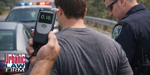 Daytime photo of an Oklahoma police officer standing with a driver on the roadside while a handheld breath tester shows 0.16, illustrating a first-time aggravated DUI Oklahoma traffic stop and the high stakes that call for experienced Oklahoma criminal defense representation by The Urbanic Law Firm.