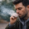 Man smoking marijuana outdoors in a daytime scene, illustrating Oklahoma drug defenses and Oklahoma criminal defense by The Urbanic Law Firm.
