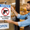 Business owner posting a no-firearms sign on a storefront door, illustrating business owner gun rights in Oklahoma criminal defense content by The Urbanic Law Firm.