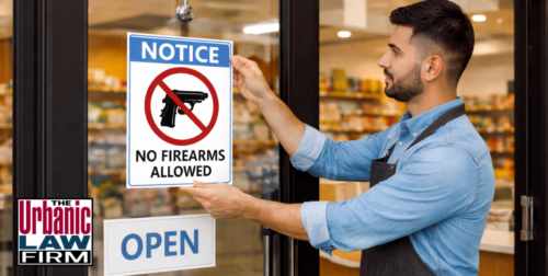 Business owner posting a no-firearms sign on a storefront door, illustrating business owner gun rights in Oklahoma criminal defense content by The Urbanic Law Firm.