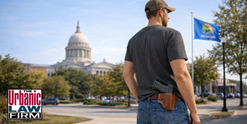 Man with a holstered pistol standing outdoors in Oklahoma near the State Capitol, illustrating Oklahoma constitutional carry and Oklahoma criminal defense by The Urbanic Law Firm.