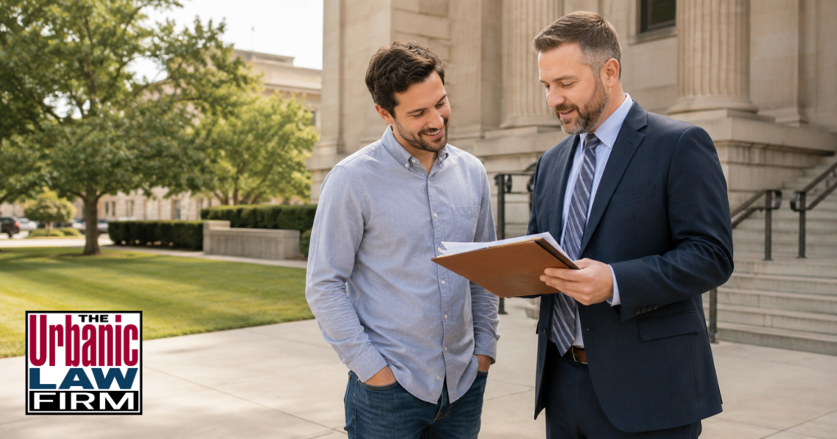 Attorney reviewing Oklahoma 991c expungement paperwork with a client outside a courthouse, illustrating criminal defense record update help by The Urbanic Law Firm.