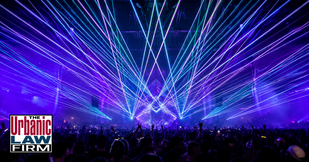 Crowded Oklahoma rave with stage lasers, haze, and raised phones, illustrating Oklahoma laser interference offenses and criminal defense help from The Urbanic Law Firm.
